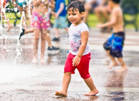 Boy in park enjoying sprinklers