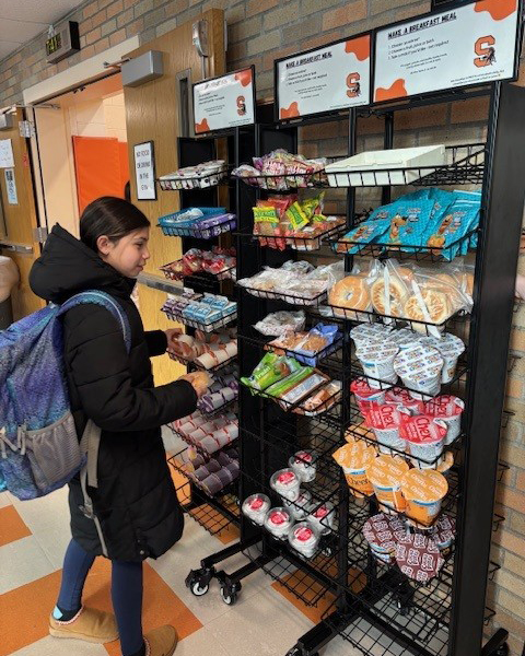 Middle school student getting breakfast from grab and go breakfast cart